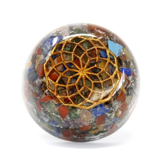 A multifaceted, gem-filled sphere displays a raised gold filigree pattern at its peak. The ornament sits on a plain, white background.