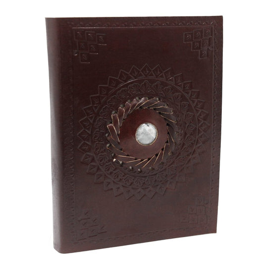 A brown leather journal features a circular design with a central stone. The cover has embossed patterns and is set against a white backdrop.