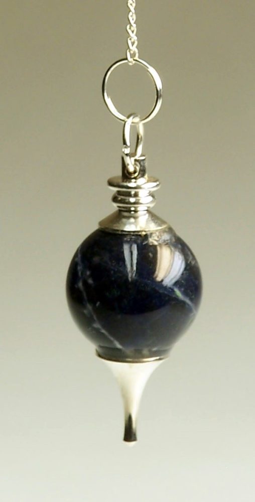 A sodalite pendulum, with a silver chain and hardware, dangles against a neutral background. The sodalite is shaped like a sphere, and has a silver tip.