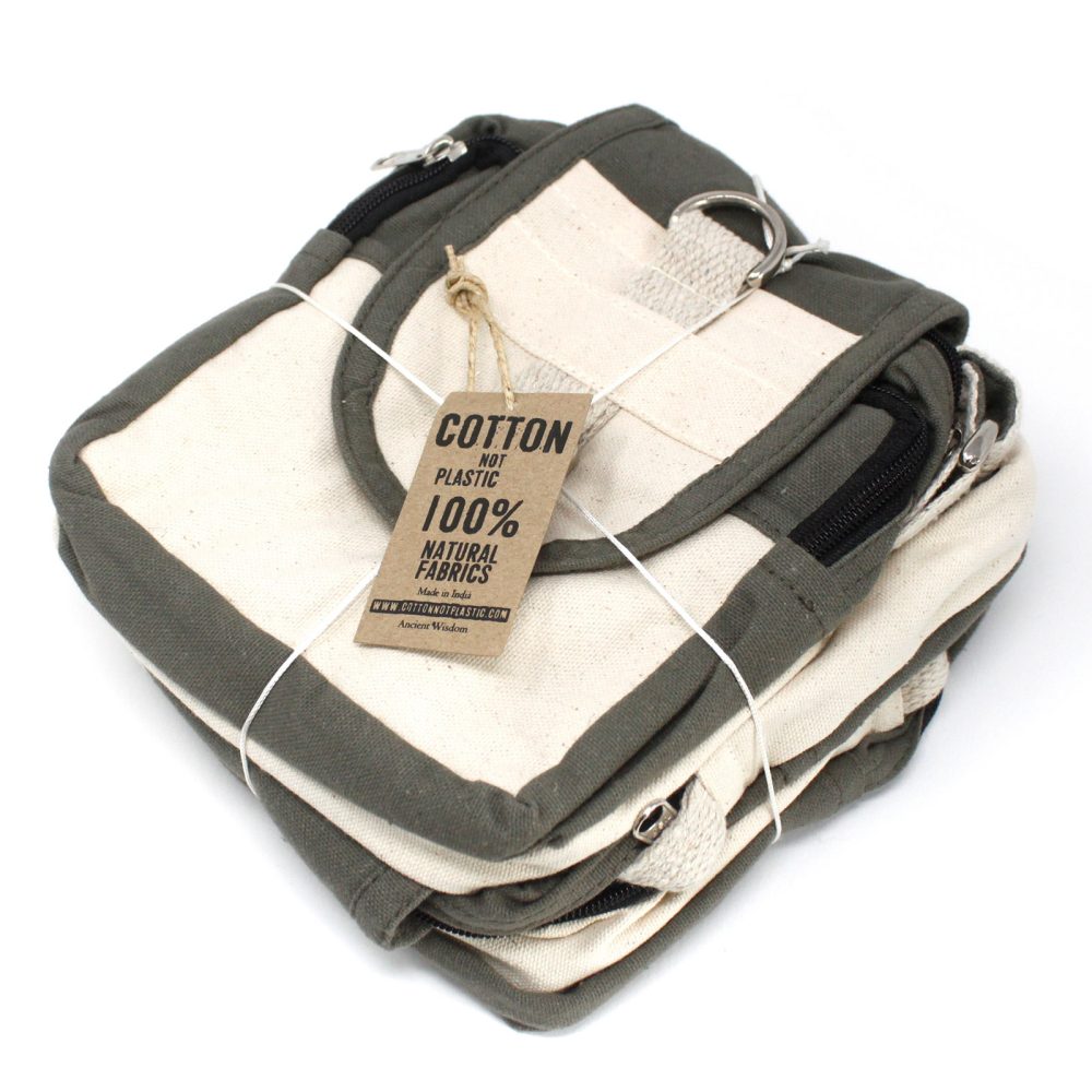 The folded, square, canvas bag with a green trim is tied with twine; it features a tag reading “COTTON NOT PLASTIC 100% NATURAL FABRICS Made in India WWW.COTTONNOTPLASTIC.COM Ancient Wisdom.” The bag is on a white surface.