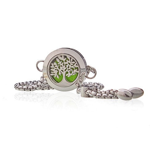 A silver-toned pendant with a tree design inset against a green background lies on a silver chain against a bright white background.