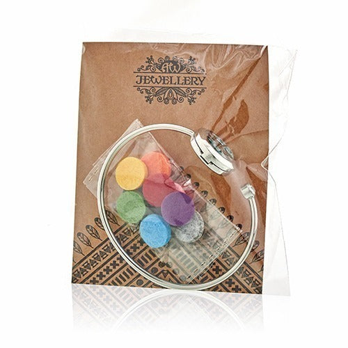 A silver aromatherapy bracelet, with colorful felt inserts in a plastic bag, sits in front of a brown backing in a clear plastic bag. Text on the backing reads "JEWELLERY".
