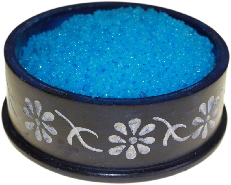Blue granules rest in a dark, flower-decorated bowl.