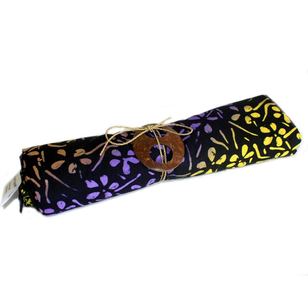 A batik fabric, rolled and tied with twine and a coconut shell, lies on a white background.