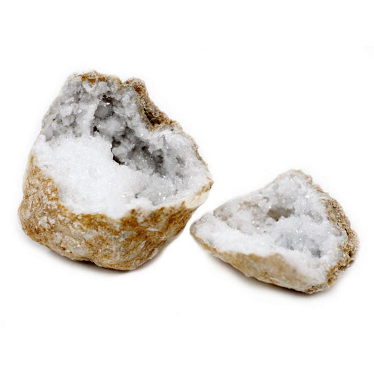 Two geode halves sit open on a bright white surface. The rough, tan exteriors give way to sparkling, white crystal interiors.