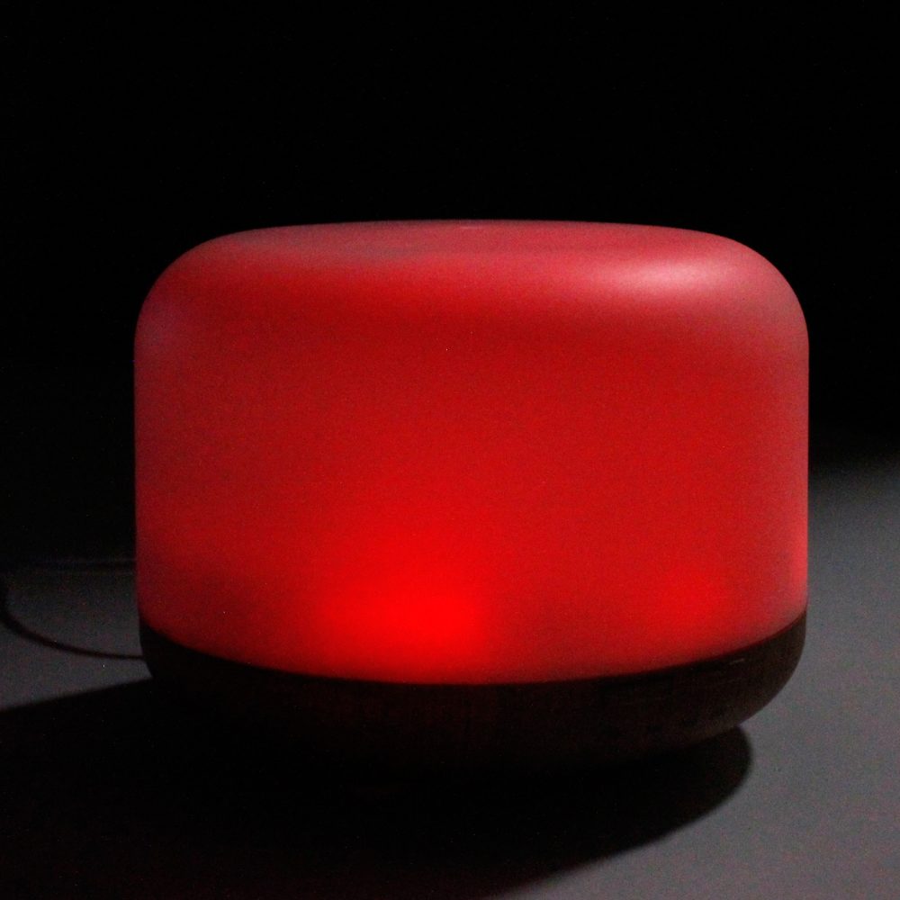 A short, cylindrical, red lamp glows on a black surface against a dark background.