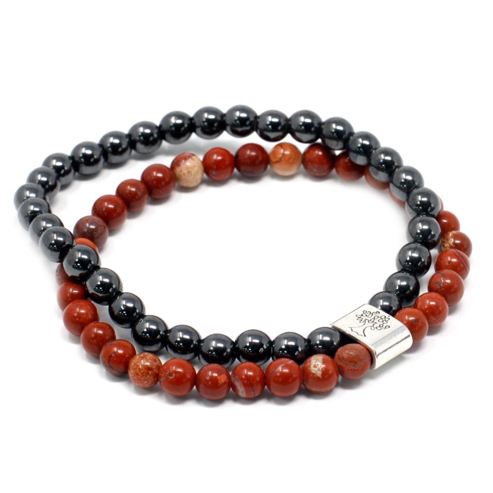 Two beaded bracelets, one black and one red, are coiled next to each other, in a simple, white setting.