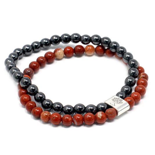 Two beaded bracelets, one black and one red, are coiled next to each other, in a simple, white setting.