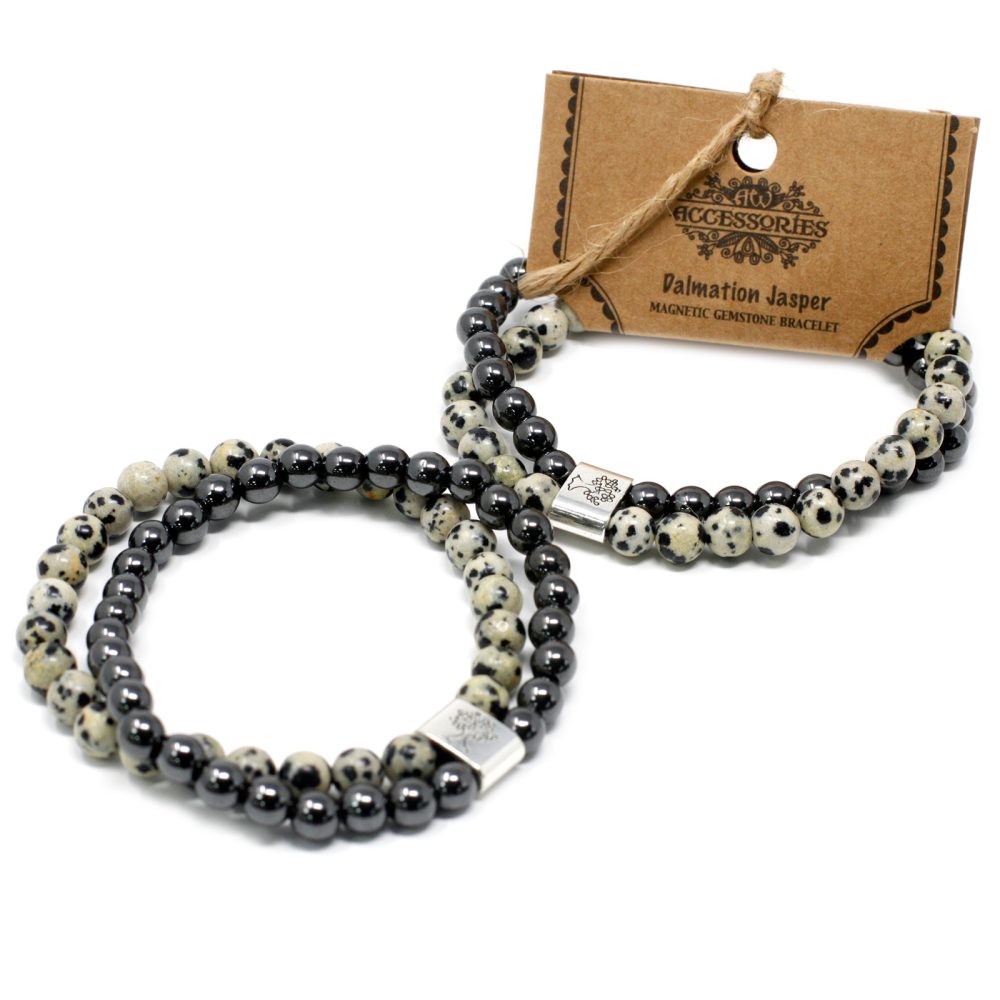 Two beaded bracelets, made of black beads and Dalmatian Jasper beads, lie on a white surface; they are paired with a tag reading "Accessories - Dalmatian Jasper MAGNETIC GEMSTONE BRACELET".