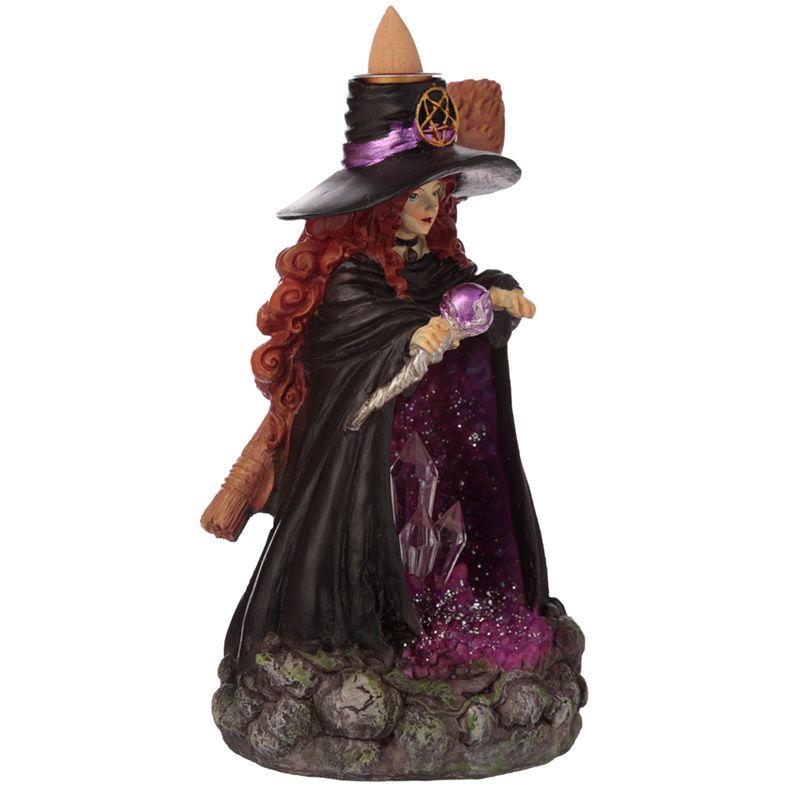 Figurine of a witch holding a crystal ball, wearing a black hat adorned with a pentacle, standing on rocky base, with purple crystals and shimmering cloak, possibly an incense holder.