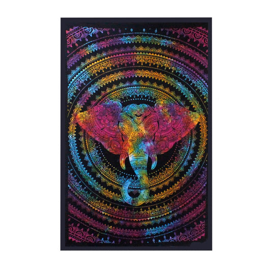 An elephant's head, decorated with colorful mandala patterns, is displayed on a tie-dye tapestry. The tapestry hangs against a plain background.