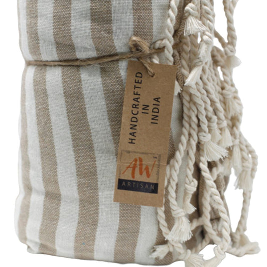 A beige and white striped textile is rolled and tied with twine. A tag reads: HANDCRAFTED IN INDIA, AW ARTISAN.