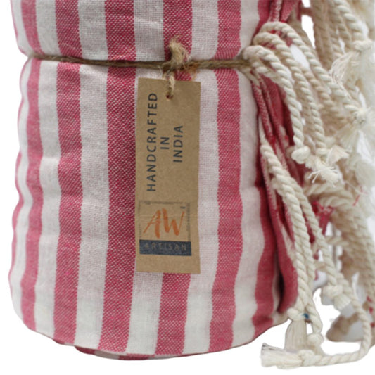 A pink and white striped towel is rolled and tied with twine. A tag reads "HANDCRAFTED IN INDIA" and "AW Artisan".