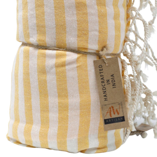 A yellow and white striped towel is rolled and tied. A tag reads, “HANDCRAFTED IN INDIA” and features a logo: “AW ARTISAN”.