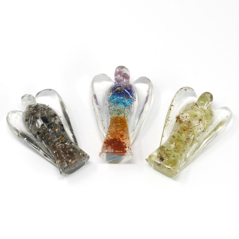 Three resin angel figurines, each filled with different materials like stones and metal shavings, stand upright on a white surface.