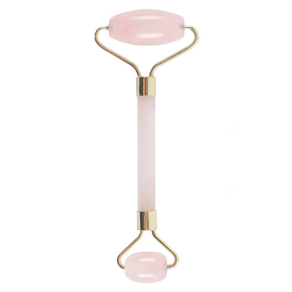 A pink gemstone facial roller sits still against a white background. The handle is gold, and the stones are light pink, nearly white in color.