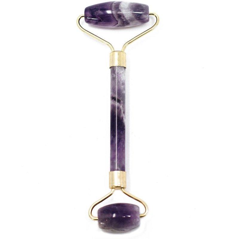A purple amethyst face roller, encased in gold-colored metal, faces forward in a white background.