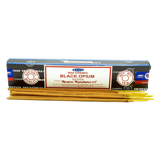 Incense sticks are placed in front of a rectangular box labeled "Satya Nag Champa Black Opium Incense" by "Shrinivas Sugandhalaya LLP," with additional product information and weight "15 g".