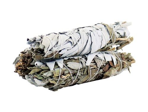 Two tied bundles of sage are stacked. The sage has mostly white leaves and some dark green, brown leaves. The background is white.