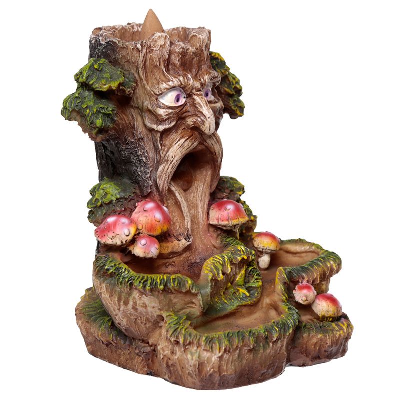 A tree trunk with a carved face, displaying a surprised expression, is surrounded by green leaves and red mushrooms. It serves as an incense holder, with smoke flowing through its mouth.