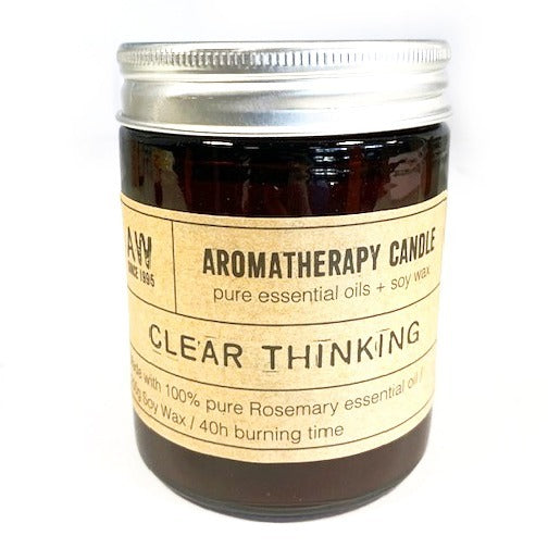 A brown glass candle sits on a surface. It is an aromatherapy candle, labeled "CLEAR THINKING," made with rosemary essential oil and soy wax, and has a 40-hour burn time.