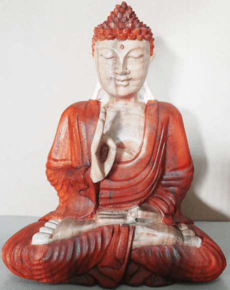 A seated Buddha statue, depicted in meditation with hand gestures, is made of wood with red and white colors. It is set against a plain, light-colored background.