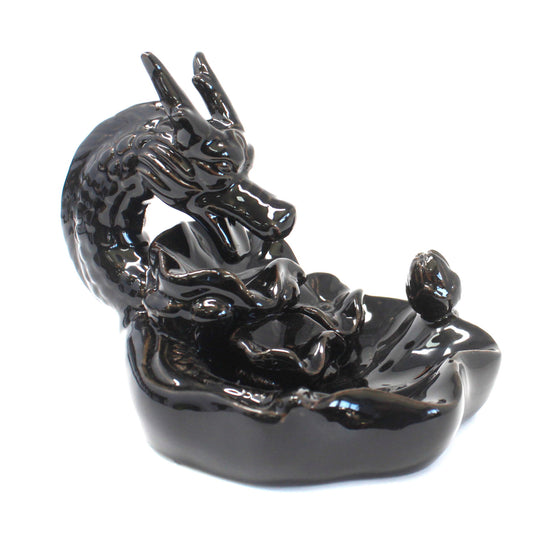 A glossy black ceramic dragon sculpture winds around a lotus-shaped incense holder on a smooth surface, creating an elegant and mystical appearance.