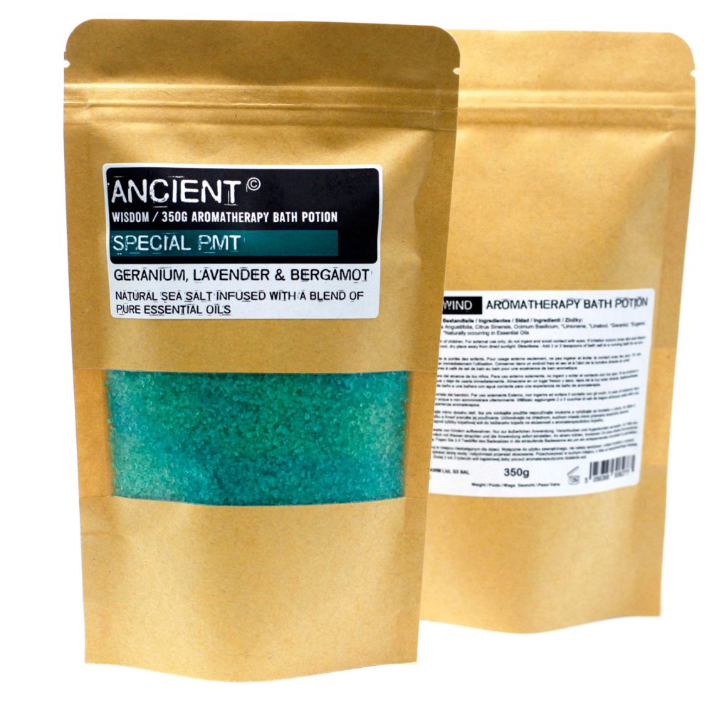 Two brown, stand-up pouches containing aromatherapy bath potions appear. The left pouch displays "ANCIENT WISDOM / 350G AROMATHERAPY BATH POTION, SPECIAL PMT, GERANIUM, L'AVENDER & BERGAMOT, NATURAL SEA SALT INFUSED WITH A BLEND OF PURE ESSENTIAL OILS" and has a clear window revealing turquoise-colored bath salts.