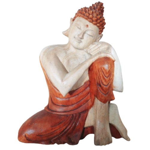 A serene wooden Buddha statue, with eyes closed, sits resting its head on one knee, draped in a flowing robe, against a plain white background.