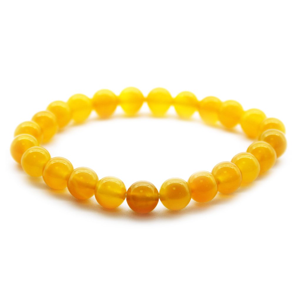 A yellow beaded bracelet forms a circular shape, resting on a plain white surface.