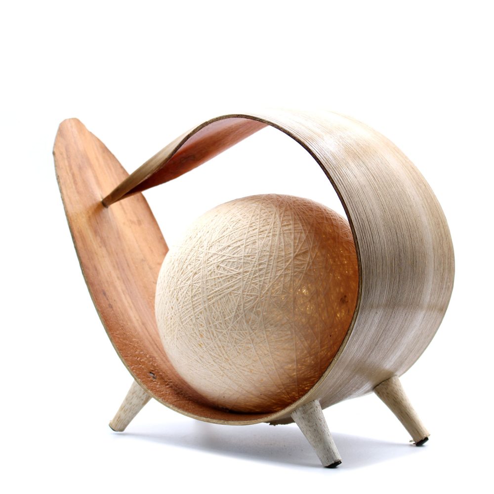 A spherical lamp, nestled within a curved wooden frame, rests on three small legs against a white background.