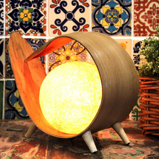 A bamboo lamp illuminates a spherical light source. It sits on a multi-colored tiled surface.