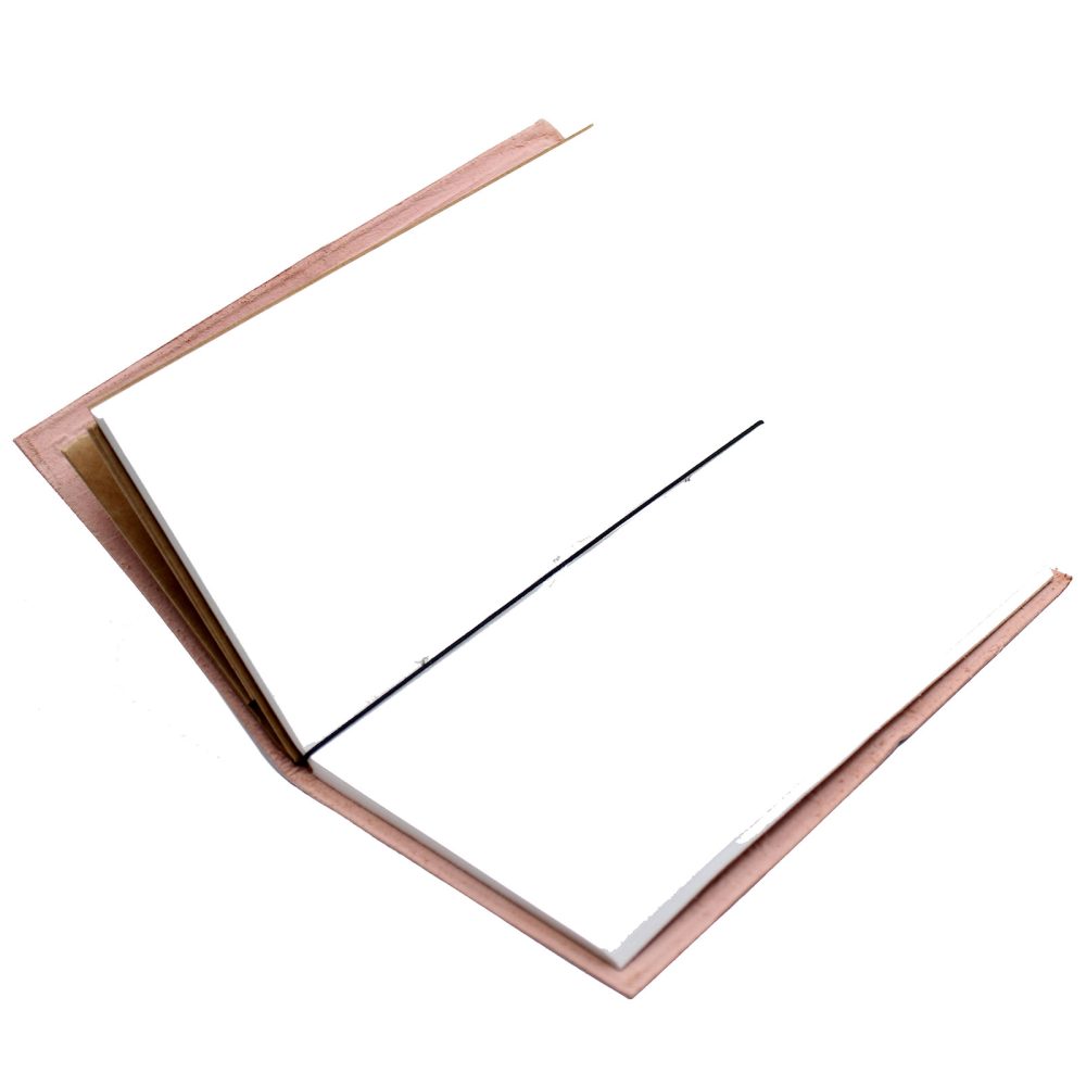 An open notebook with a pale pink cover lies against a white background. The pages are blank, and a thin black elastic band runs from top to bottom along the center.