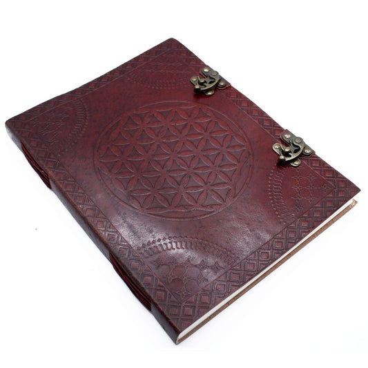 A red leather-bound journal lies flat with bronze clasps. A debossed geometric circle pattern and border decorates the front on a white background.