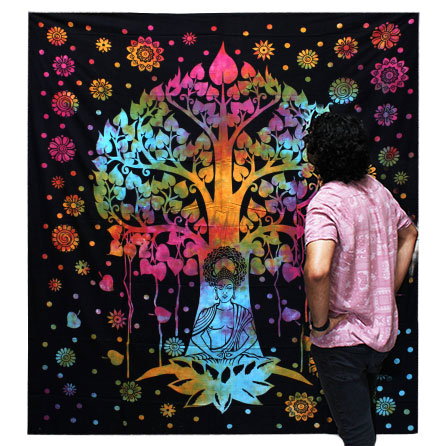 A multicolored tie-dye tapestry depicting a Bodhi tree and a meditating Buddha is viewed by a person. The tapestry features a dark background with colorful floral accents.