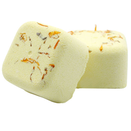 Two yellow bath bombs, adorned with dried flower petals, rest against each other on a plain white background. The flowers add texture and color to the smooth surface.