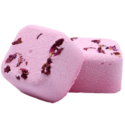 Two pink, square bath bombs with embedded dried flower petals sit on a white background, one leaning against the other.