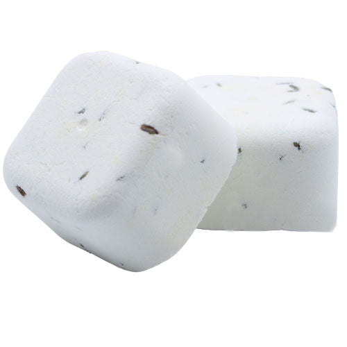 Two white, square bath bombs with small dark specks rest against each other on a plain, white background. They appear textured, indicating their purpose for use in bath relaxation.
