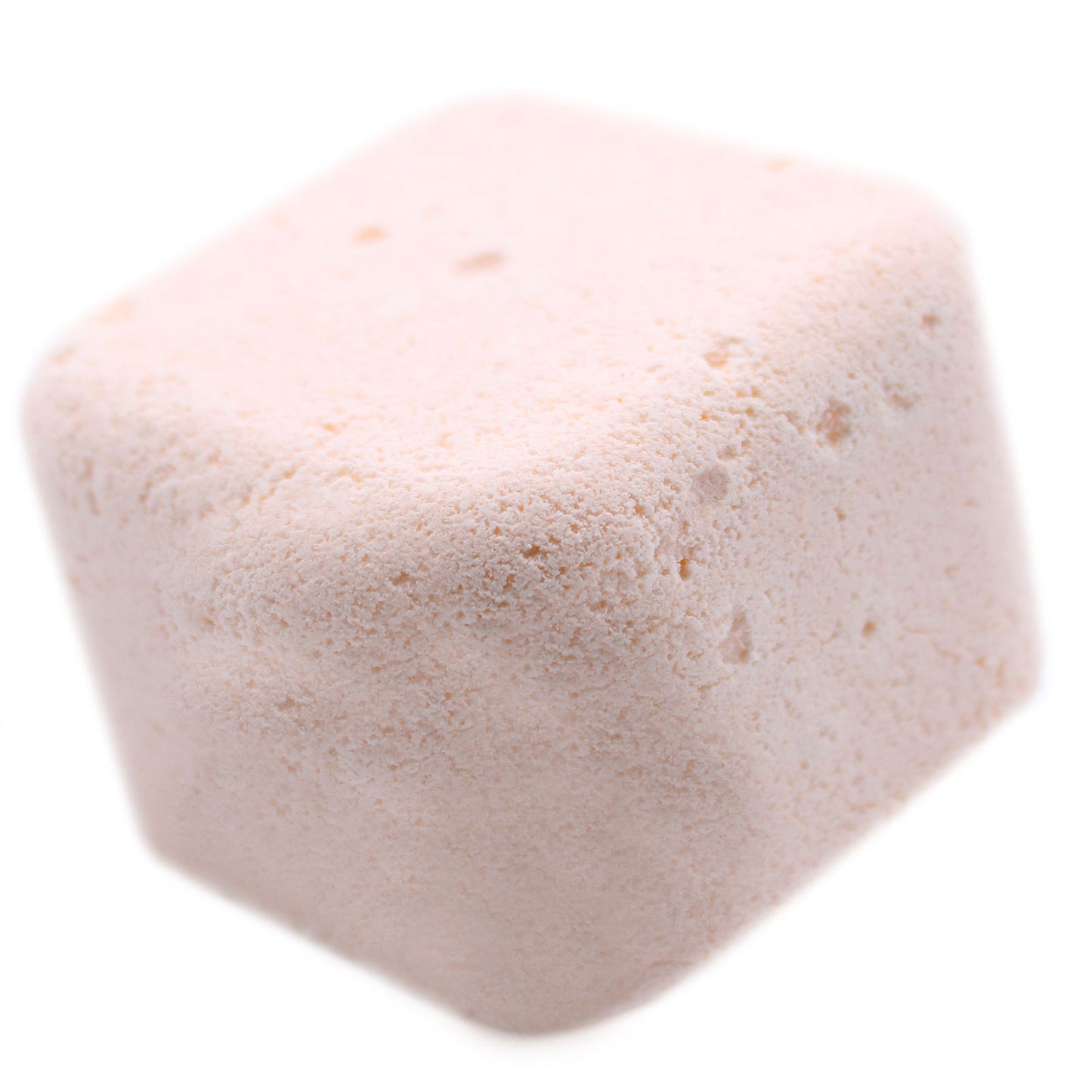 A pale pink, cube-shaped bath bomb with a lightly textured surface sits alone against a plain white background.