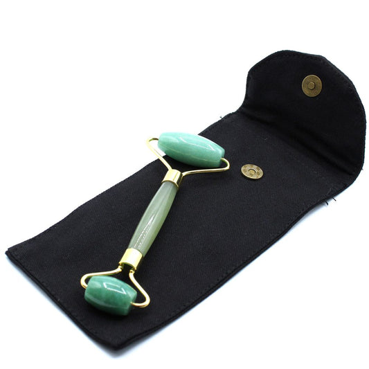 A jade roller, featuring two green rollers held by a gold frame and handle, rests on a black case with a golden snap and a flap.