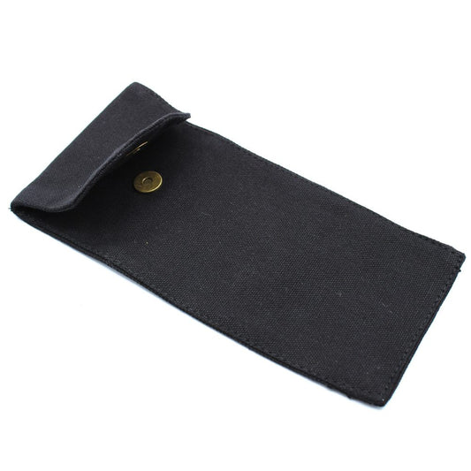 A black, rectangular canvas pouch sits open on a white surface, revealing its interior. A bronze button is visible on the flap.