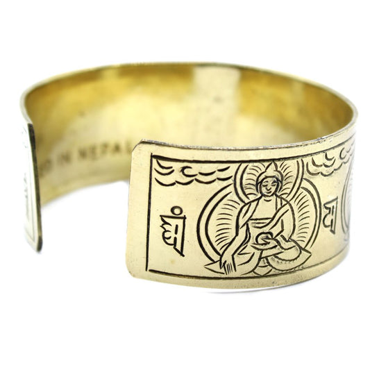 A gold bracelet displays an engraved Buddha with other designs and characters. The text "IN NEPAL" is etched into the inside of one of the ends.