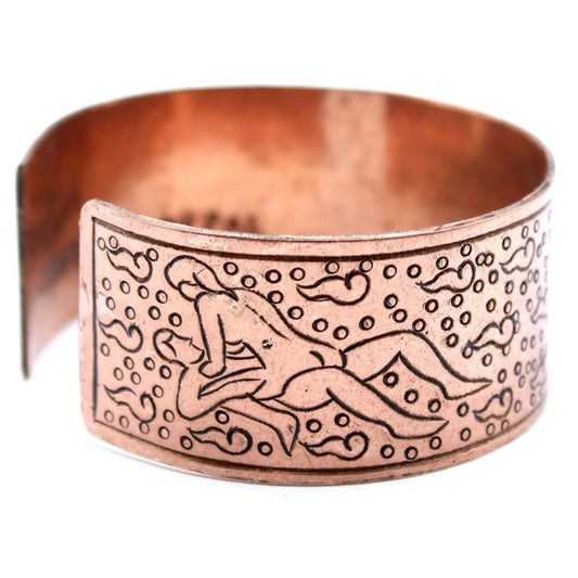 A copper-colored bracelet cuff displays a linear drawing of two people engaged in sexual activity, the illustration surrounded by abstract shapes and circles against a white backdrop.