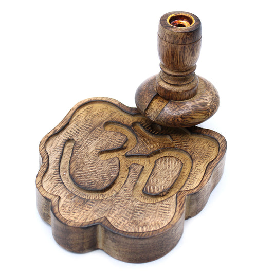 A wooden stamp with a carved "Om" symbol sits on a white surface. It consists of a textured, scalloped base and a rounded handle, used for printing.