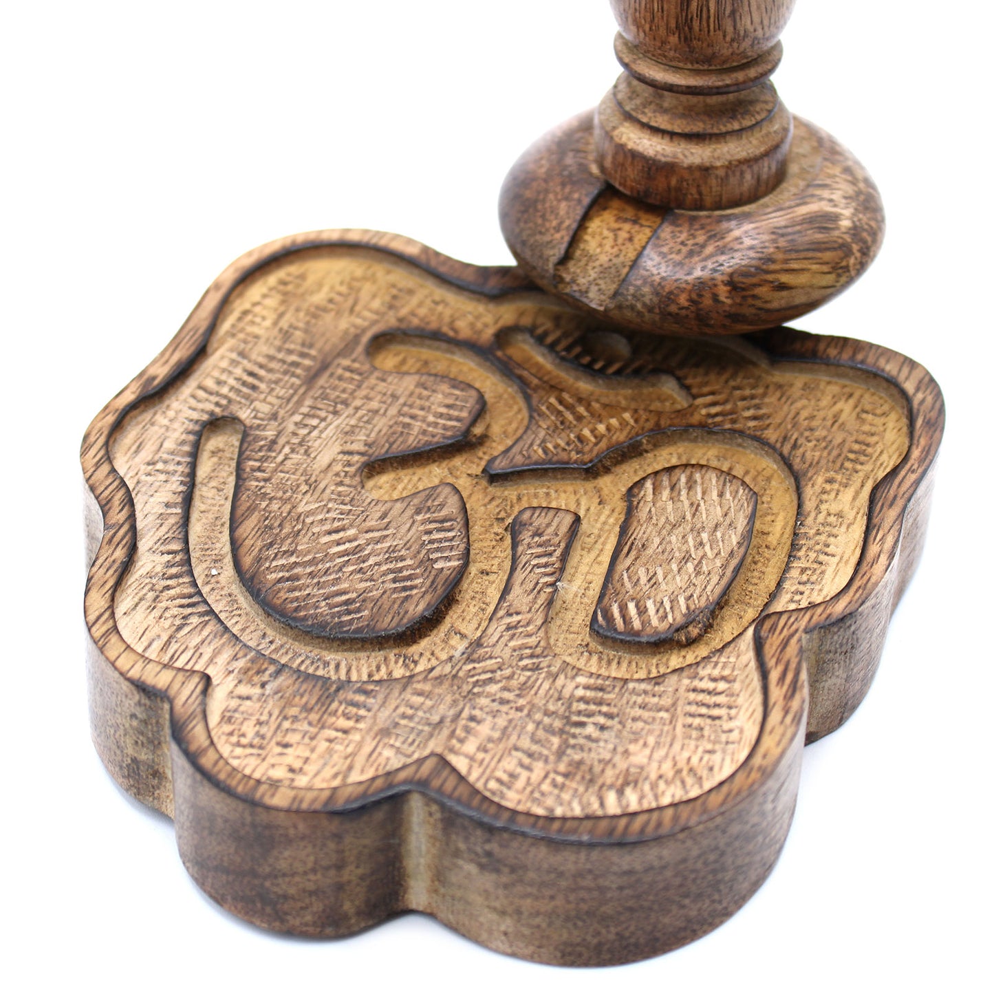 A wooden stamp with an intricately carved "Om" symbol is positioned on a white background, showing detailed woodgrain texture and a round handle for pressing.