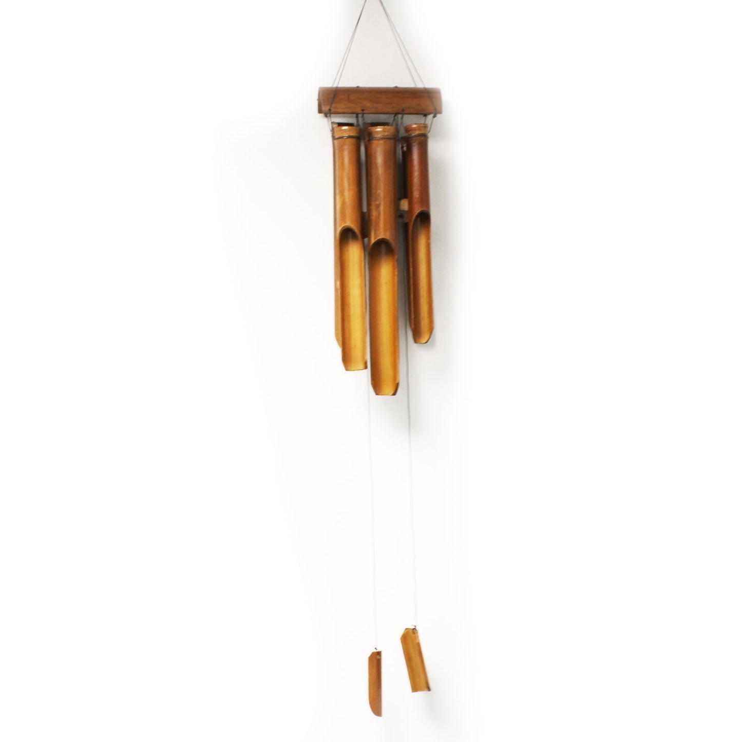 A bamboo wind chime hangs against a white wall; the tubes are suspended from a small wooden top piece.