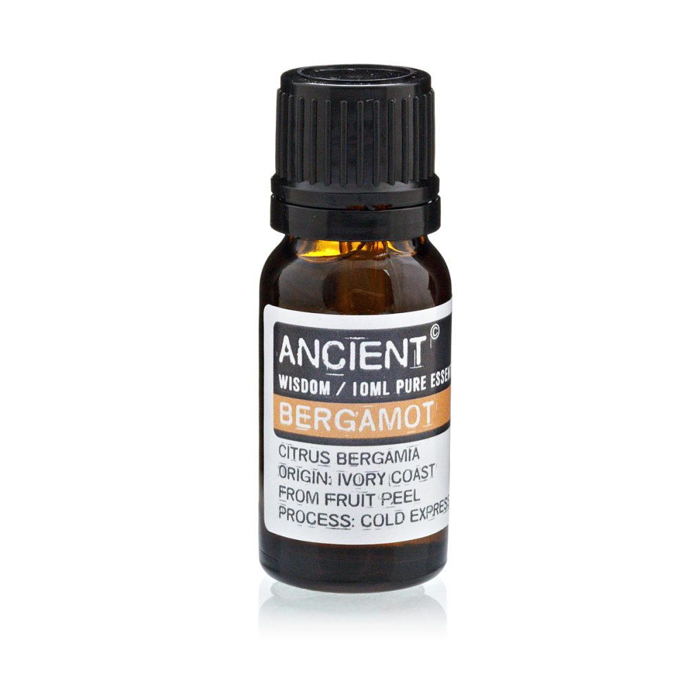 An amber-colored bottle of Bergamot essential oil is standing on a white surface. The label reads "ANCIENT, WISDOM / 10ML PURE ESSE, BERGAMOT, CITRUS BERGAMIA, ORIGIN: IVORY COAST, FROM FRUIT PEEL, PROCESS: COLD EXPRES."
