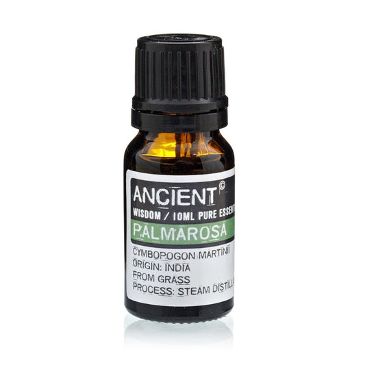 A small, amber bottle of "ANCIENT" brand palmarosa essential oil sits on a white surface. The label reads "WISDOM/10ML PURE ESSENCE", "CYMBOPOGON MARTINI", "ORIGIN: INDIA", "FROM GRASS", and "PROCESS: STEAM DISTILL".