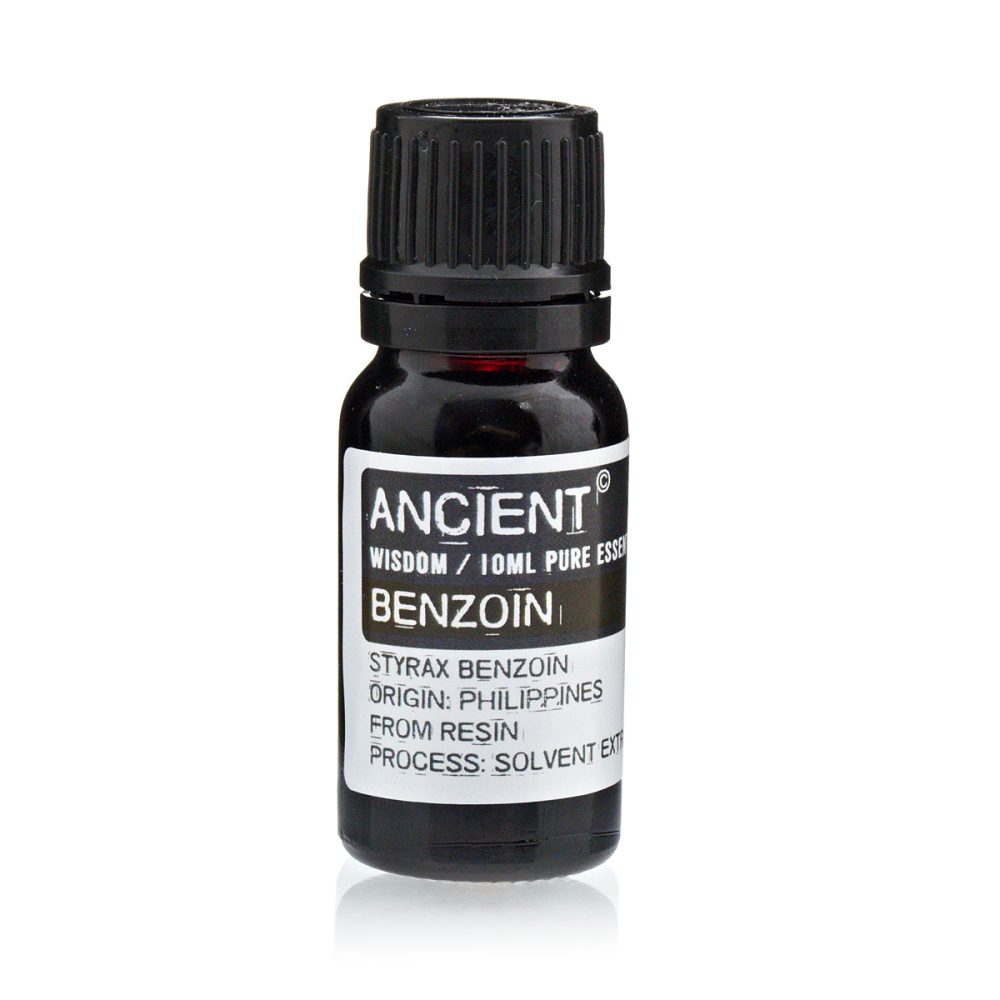 A small, dark bottle of "ANCIENT" brand benzoin essential oil stands, its label stating "WISDOM / 10ML PURE ESSENTIAL," "STYRAX BENZOIN ORIGIN: PHILIPPINES FROM RESIN PROCESS: SOLVENT EXT."