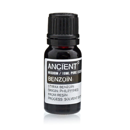 A small, dark bottle of "ANCIENT" brand benzoin essential oil stands, its label stating "WISDOM / 10ML PURE ESSENTIAL," "STYRAX BENZOIN ORIGIN: PHILIPPINES FROM RESIN PROCESS: SOLVENT EXT."